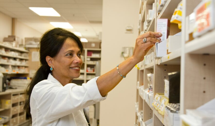 a pharmacist putting medicines to the shelf