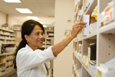 a pharmacist putting medicines to the shelf