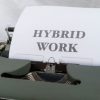 a typewriter with a sheet of paper with 'hybrid work' printed on it.